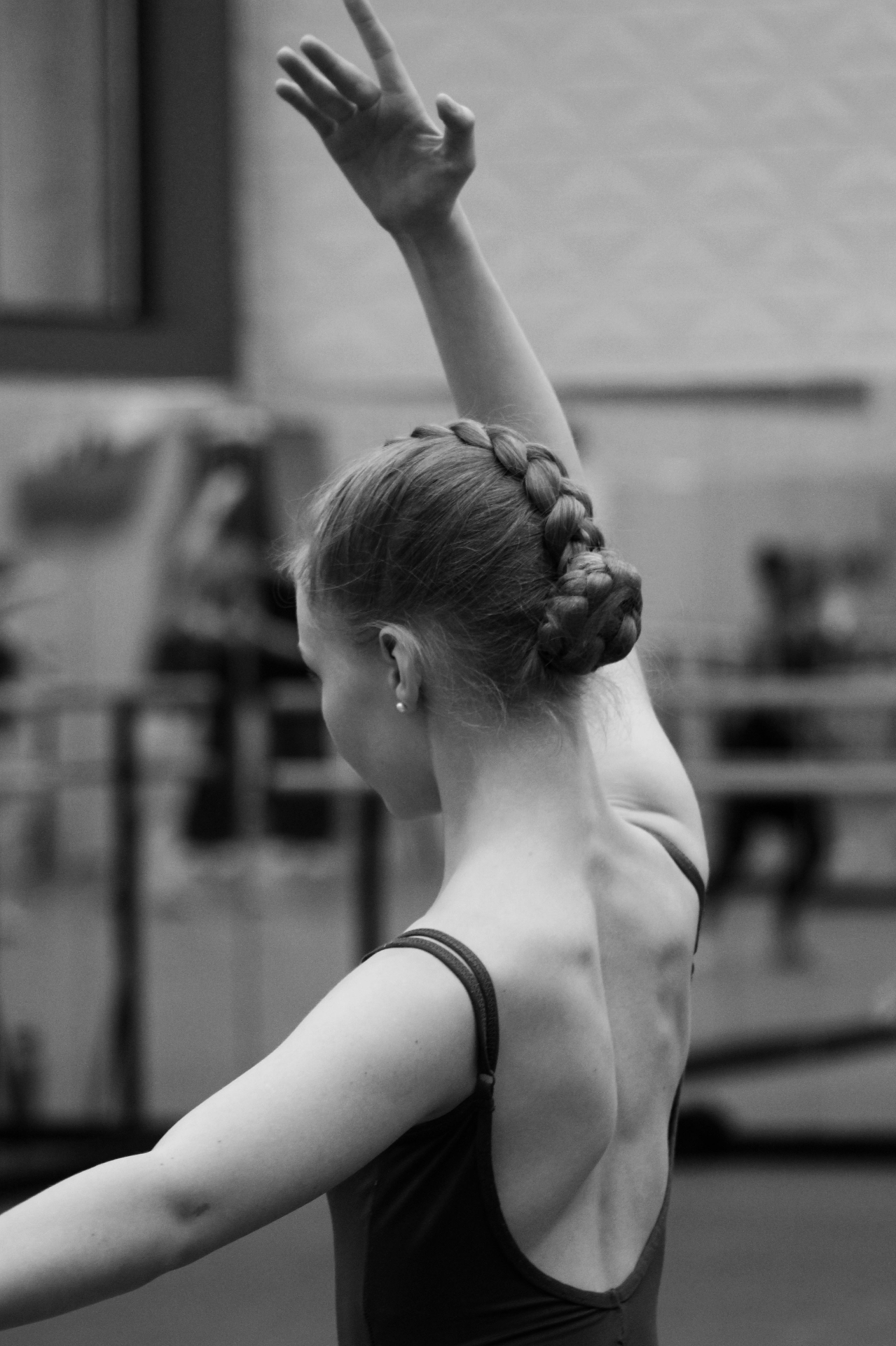 Dancer from behind with braided crown, arm raised in fifth position